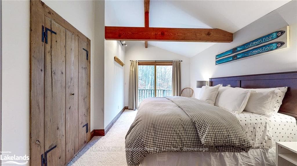 Carpeted bedroom with vaulted ceiling with beams