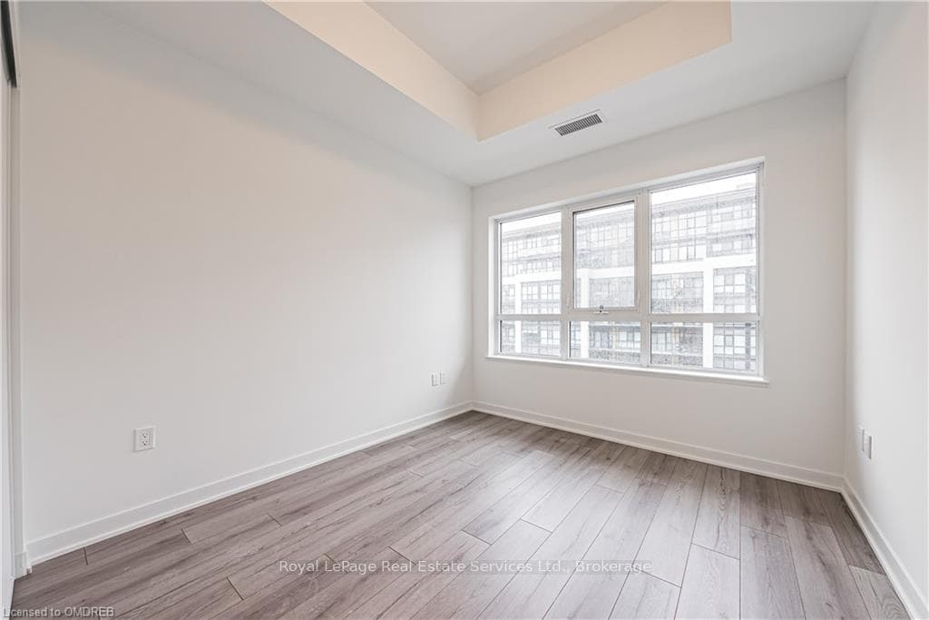 Empty room with a raised ceiling and light hardwoo