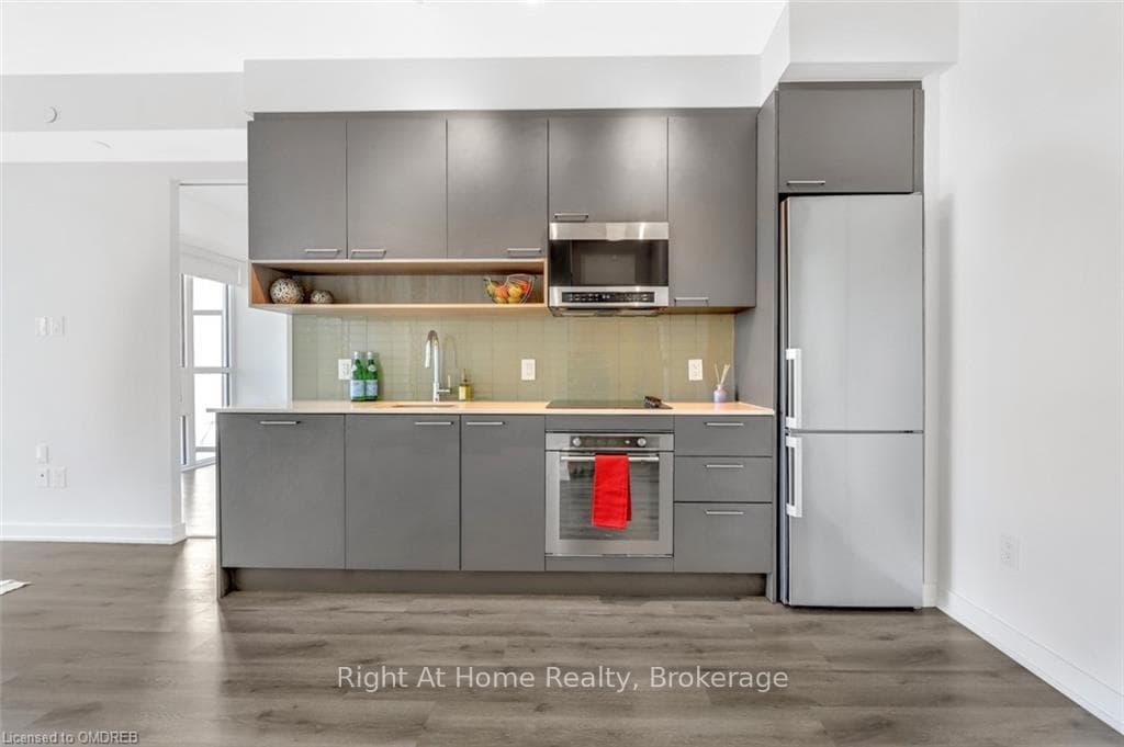 Kitchen with gray cabinetry, appliances with stain