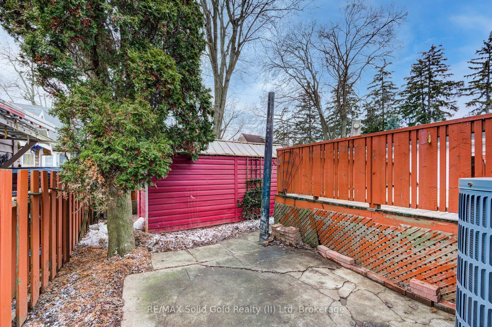 Fully fenced backyard with a shed and a patio area