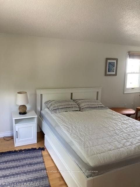 Bedroom with a textured ceiling and light hardwood