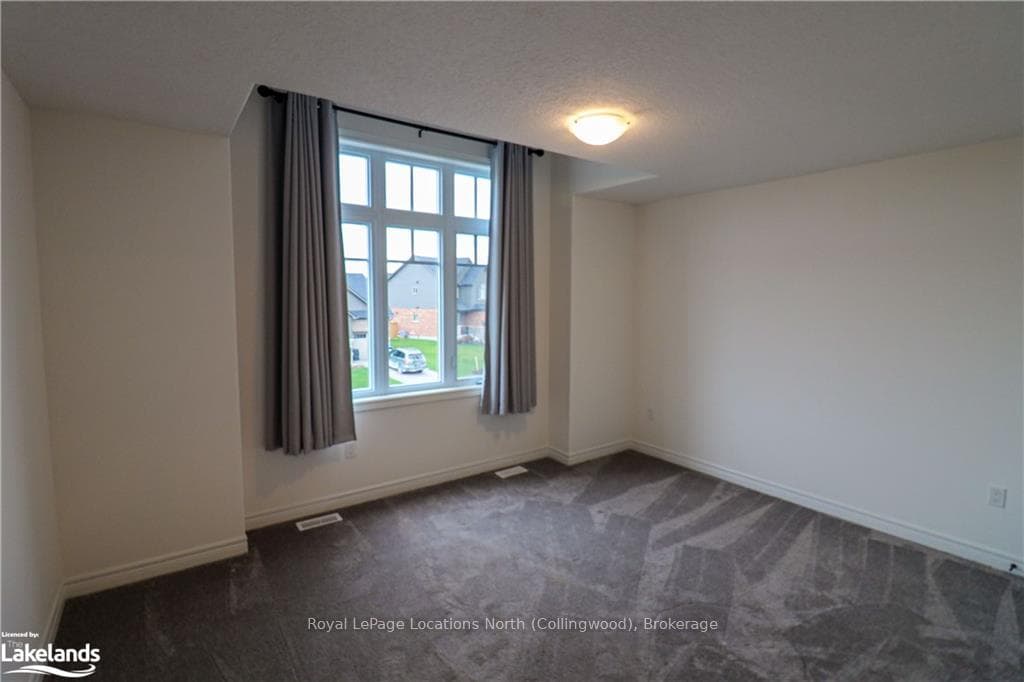 Empty room with dark carpet and a textured ceiling