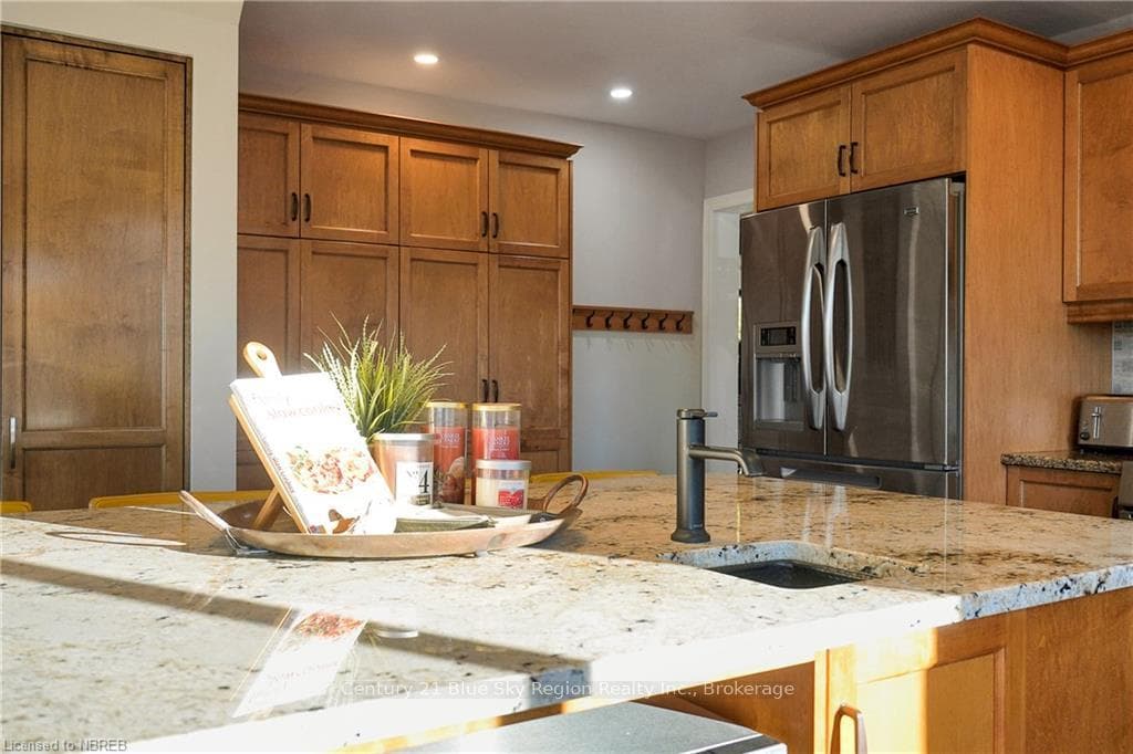 Kitchen with stainless steel fridge, sink, and lig