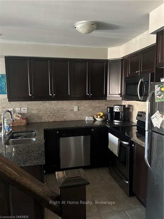 Kitchen with dark stone counters, refrigerator, di