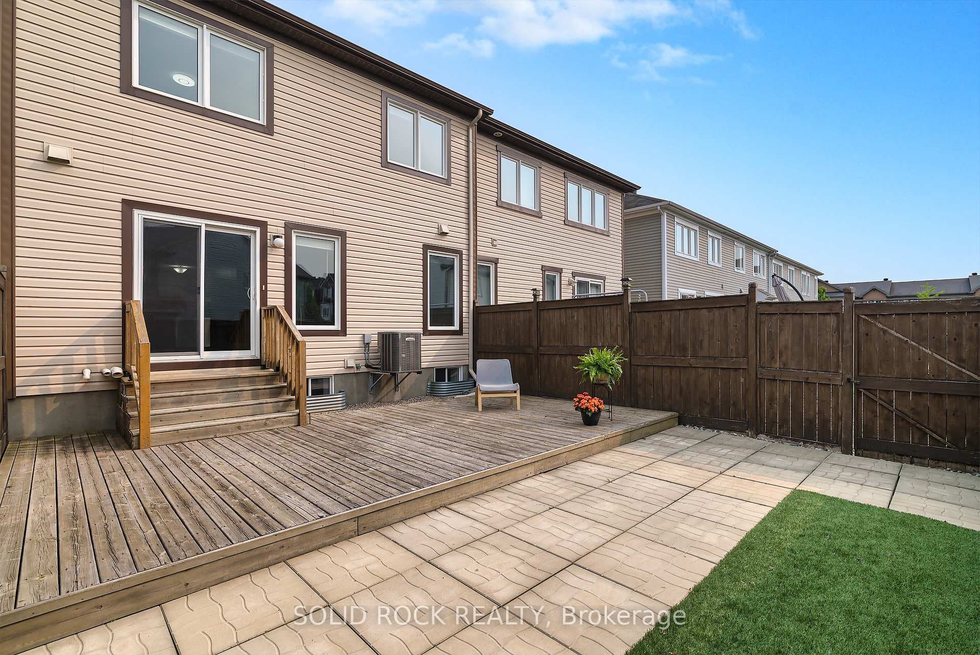 with patio stones, deck, and artificial turf.