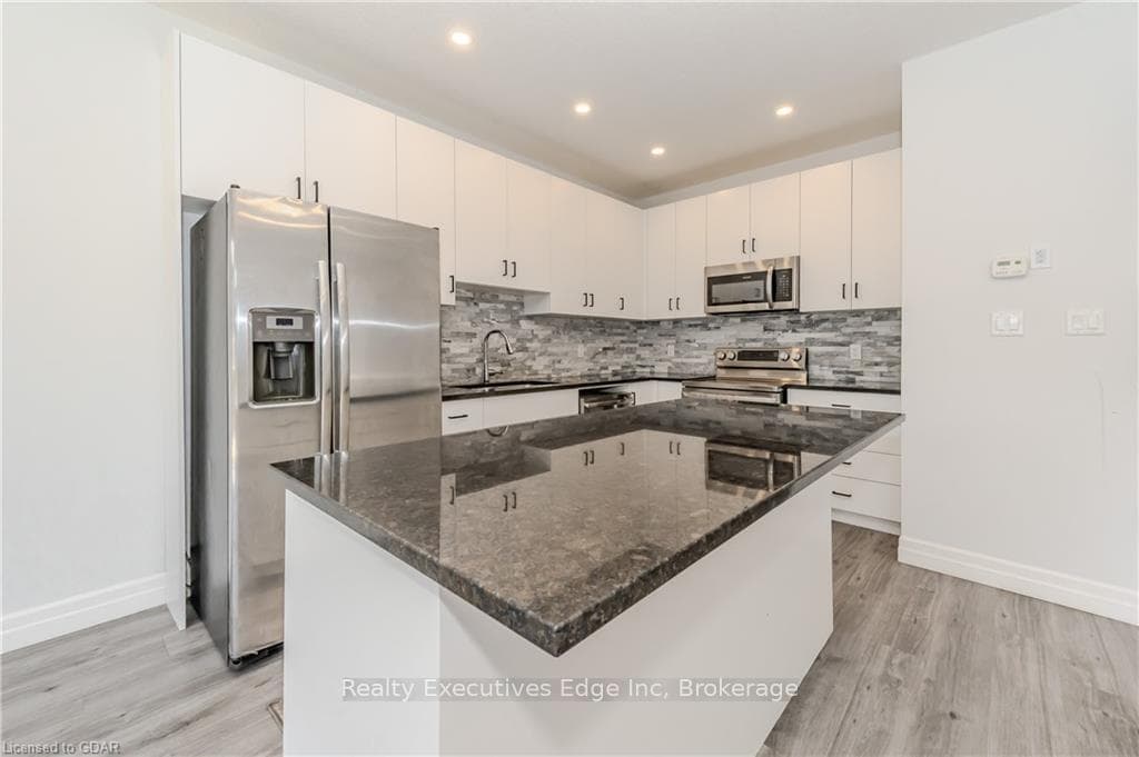 Kitchen with white cabinetry, a center island, sta