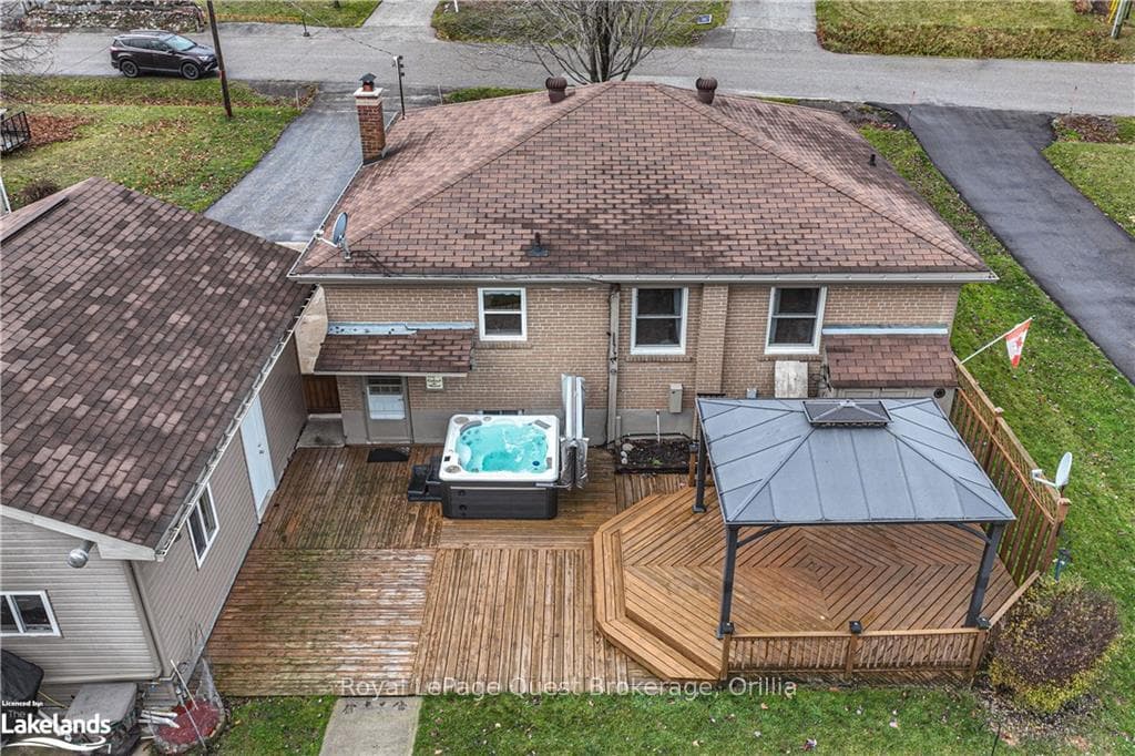 Back of property with a hot tub and a deck