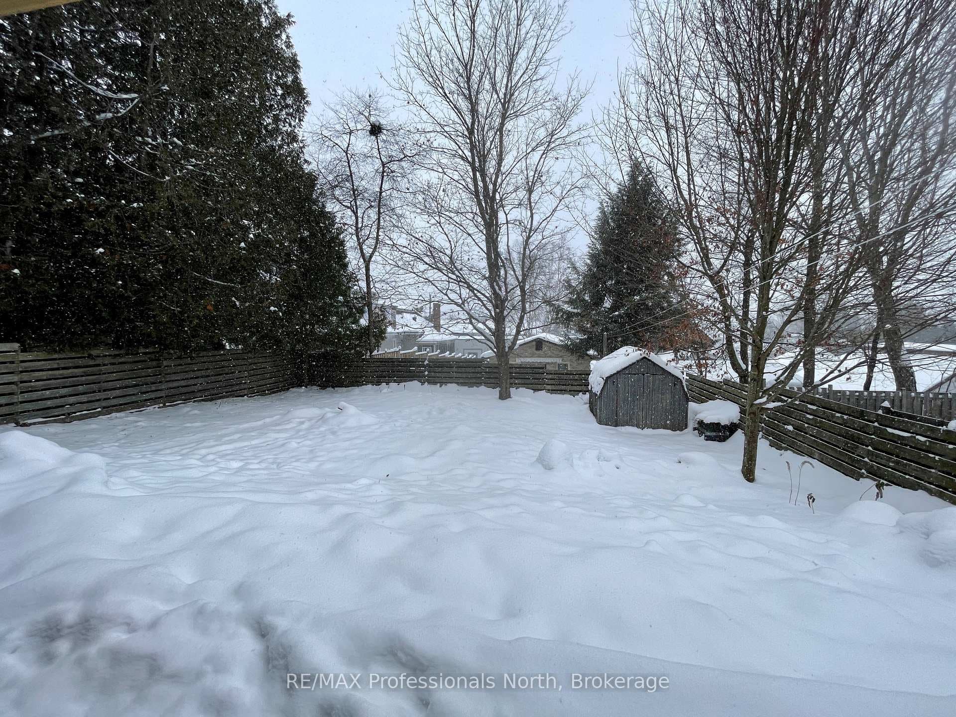Back yard fenced with treed perimeter and gardens