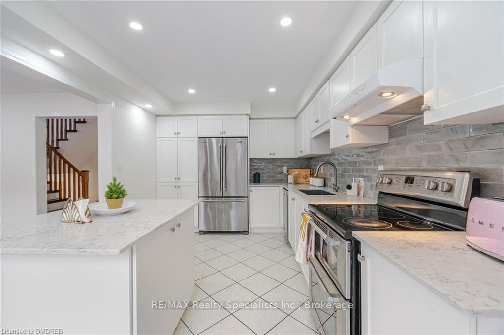Kitchen with backsplash, sink, white cabinetry, st