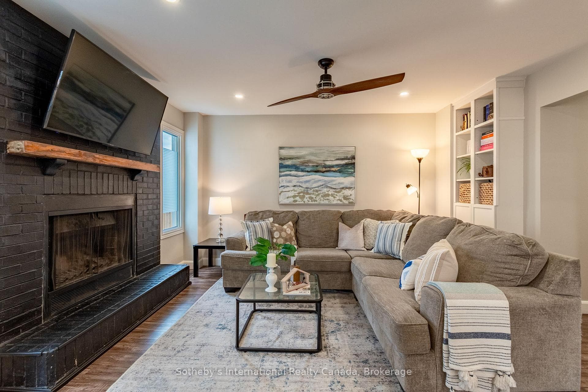 Living room with wood fireplace, open to kitchen.