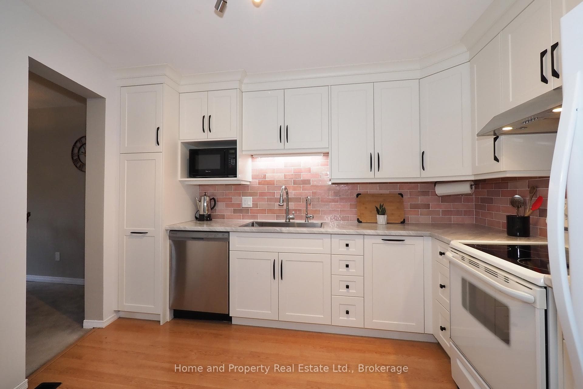 Kitchen w/ white cabinets & brick style backsplash