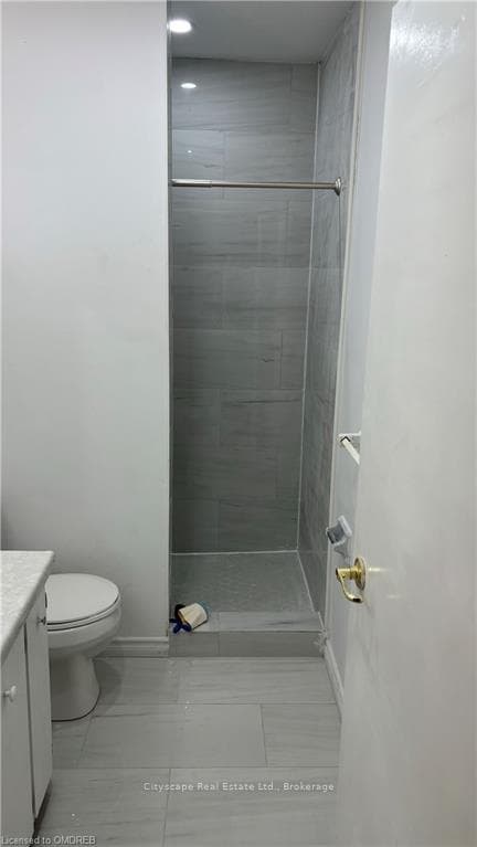 Bathroom featuring toilet, vanity, and tiled showe